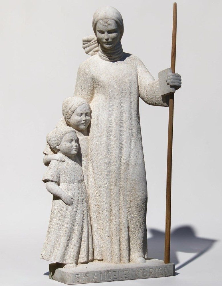 statue de sainte angele en pierre avec des fillettes et un baton